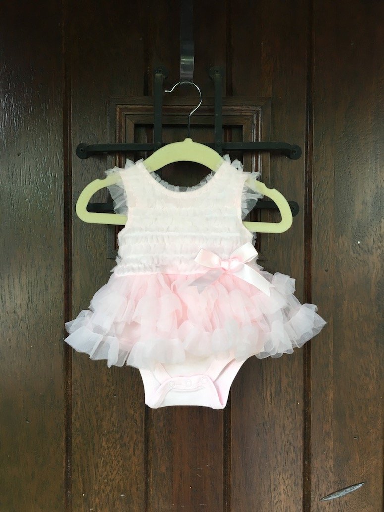 girl baby shower ideas hang outfit at front door to welcome guests. Click to see more from this beautiful Winnie the Pooh themed baby shower 