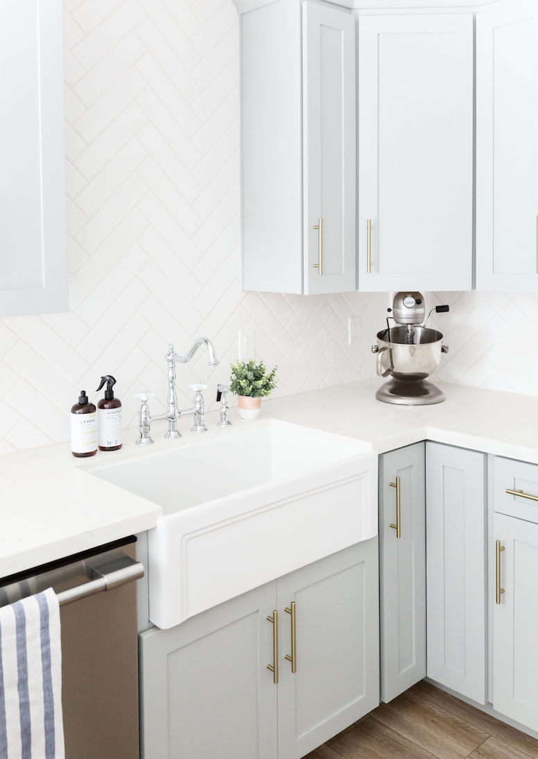 grey blue kitchen cabinets with white farmhouse sink and traditional faucet