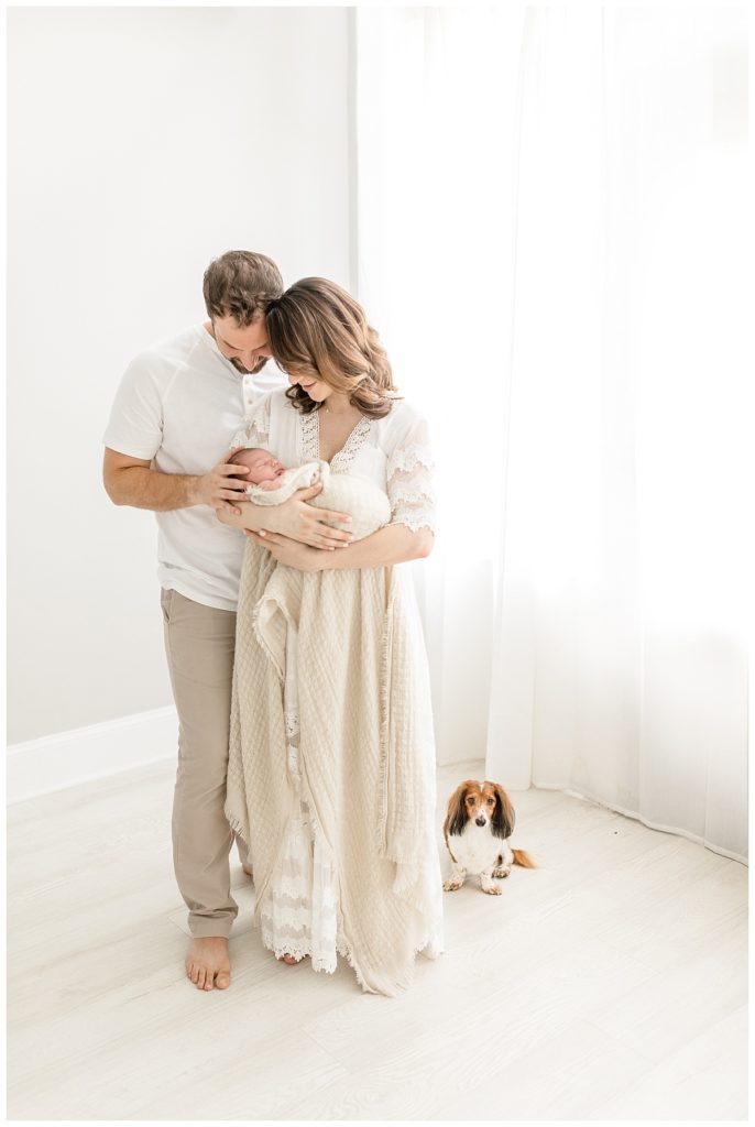 baby swaddled with two parents looking at baby