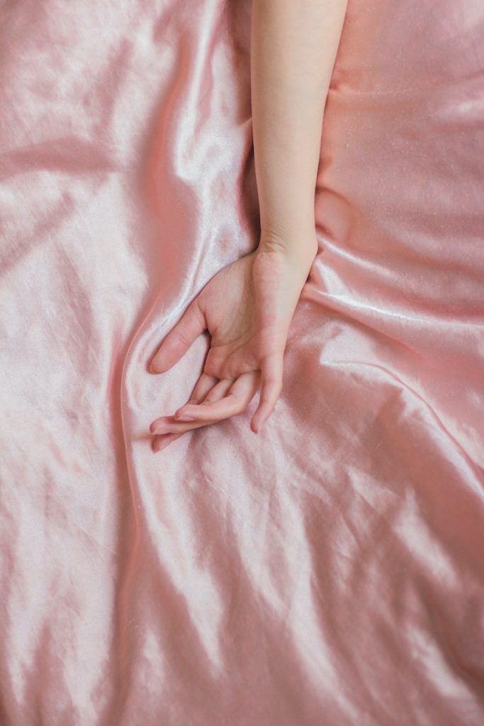 hand on pink silk sheets